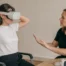 Facilitadora ayudando a una participante sentada a ajustar correctamente un visor de realidad virtual
